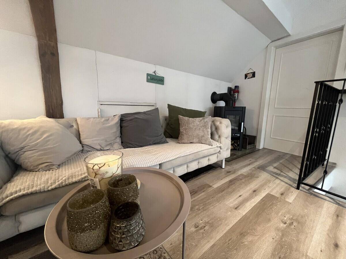 Gemütliche Sitzecke mit Sofa und einem modernen Holzofen für behagliche Wärme.