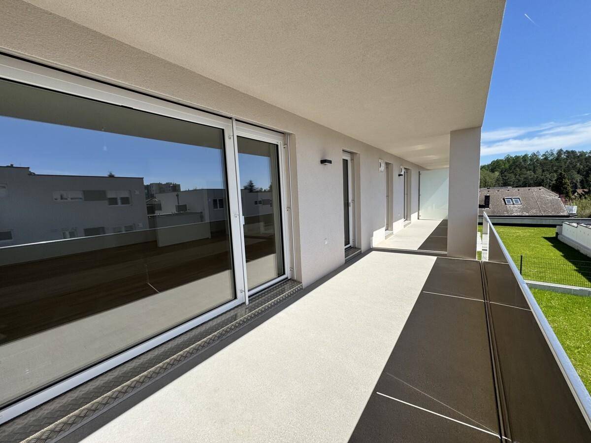 Langer Balkon mit moderner Glasbrüstung und weitem Blick auf die umliegende Bebauung.