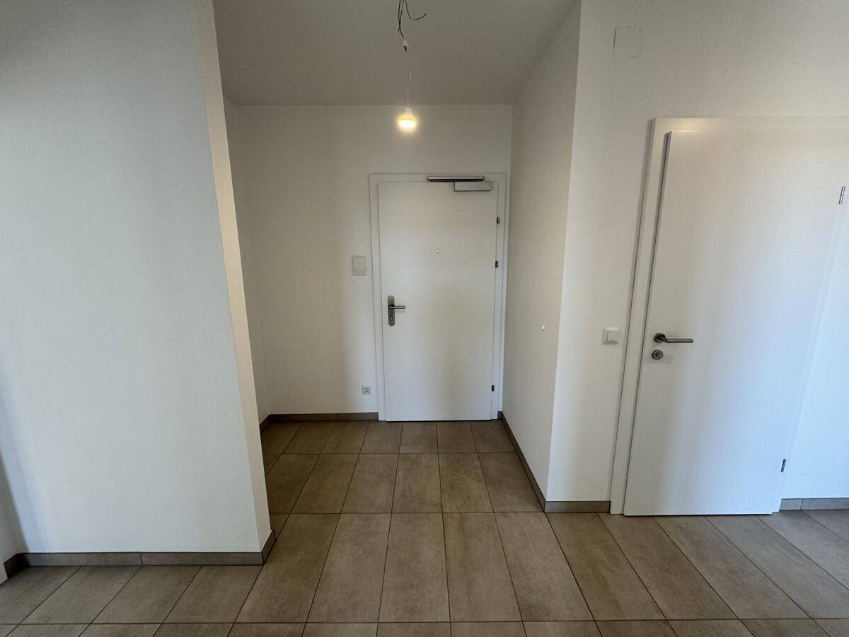 Heller Eingangsbereich mit Fliesenboden und weiß gestrichenen Wänden, einladend und funktional.