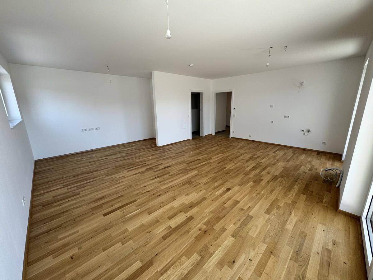Geräumiges Wohnzimmer mit Holzboden und weißen Wänden, ideal für offene Gestaltungskonzepte.