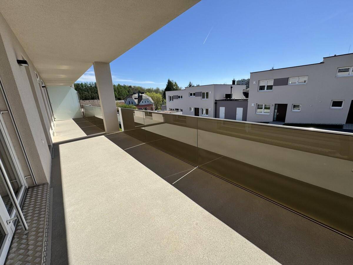 Geräumiger Balkon mit moderner Architektur und sonnigem Ausblick ins Grüne.