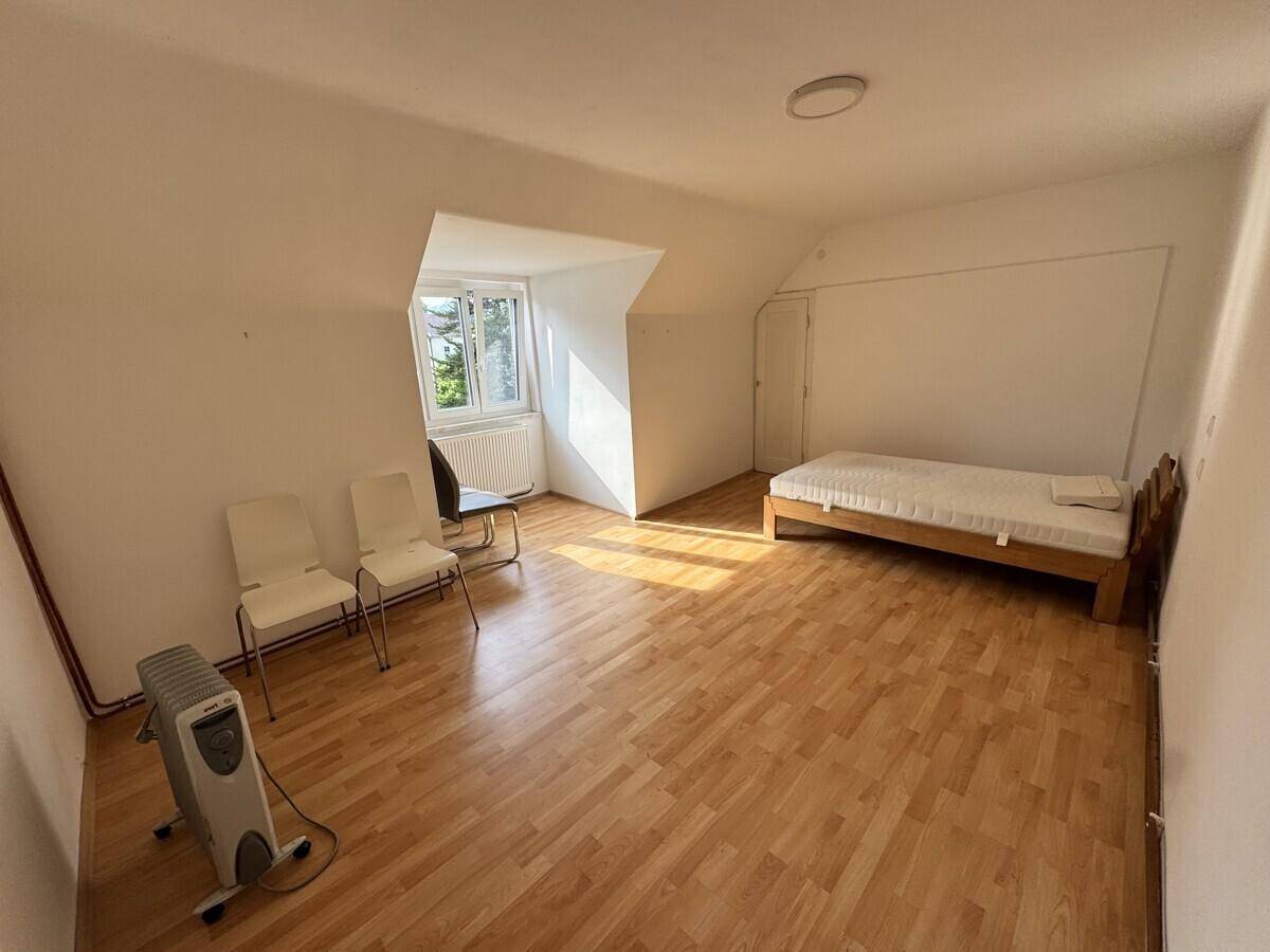 Schlafzimmer im Dachgeschoss mit Holzboden, Einzelbett und viel natürlichem Licht durch das Fenster.