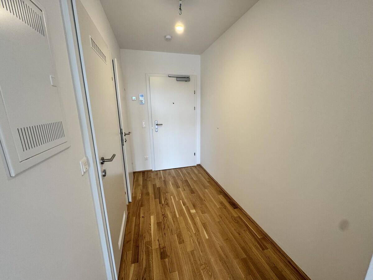 Heller Flur mit Holzboden und weißen Türen, der verschiedene Räume der Wohnung verbindet.