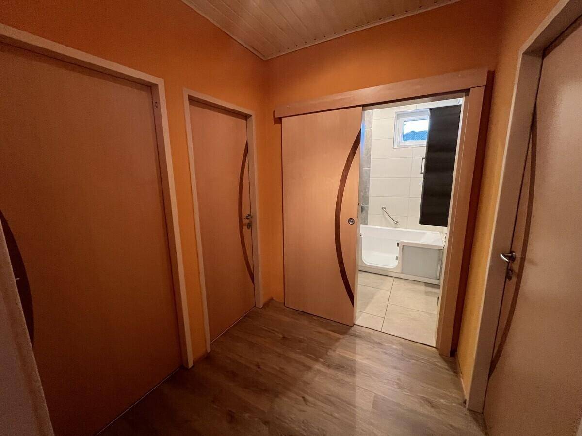 Flur mit Schiebetür, die zum Badezimmer führt, und hellem Laminatboden.