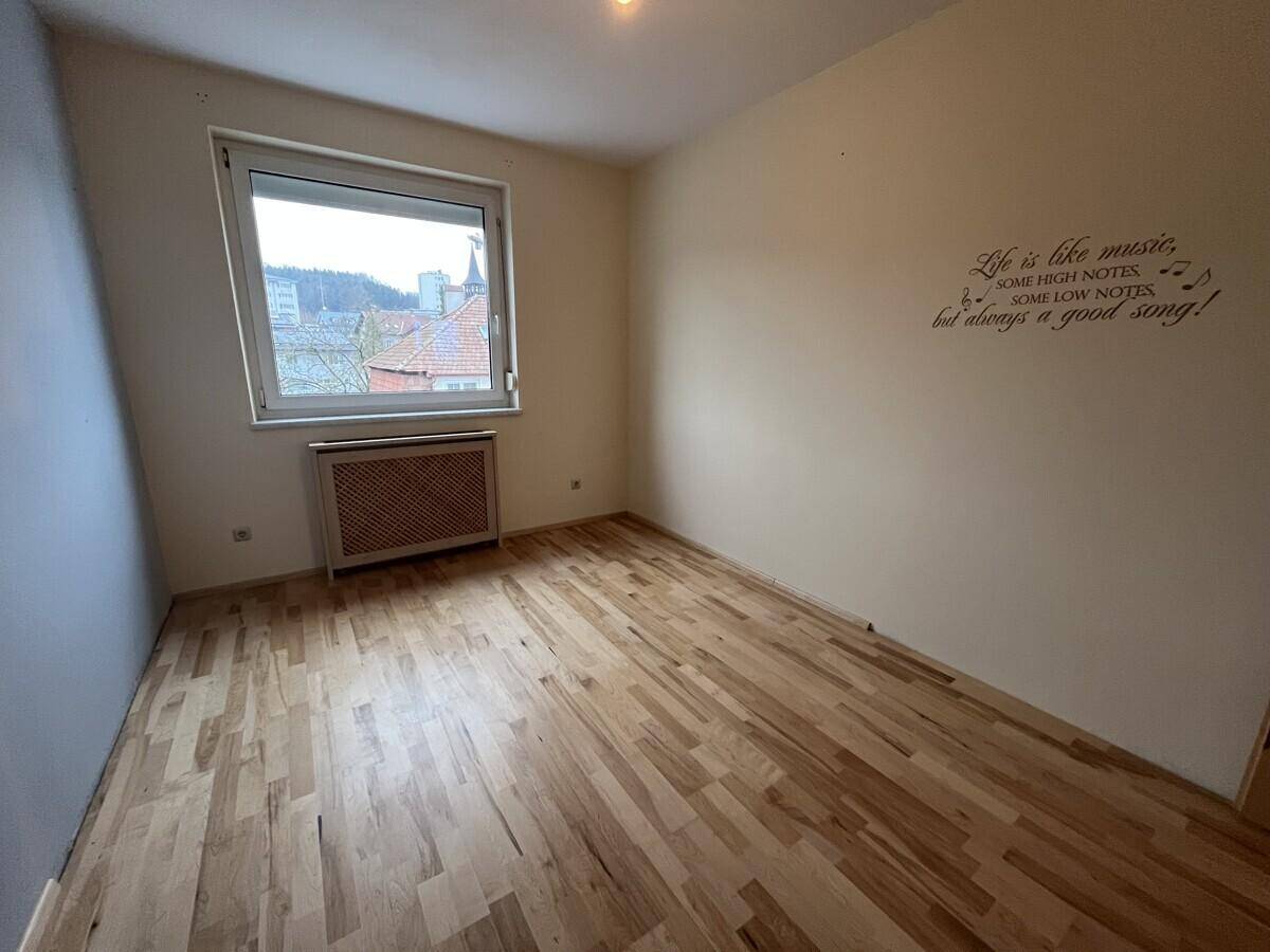 Helles Schlafzimmer mit Parkettboden und Fensterblick auf die Umgebung, ideal für Ruhe.