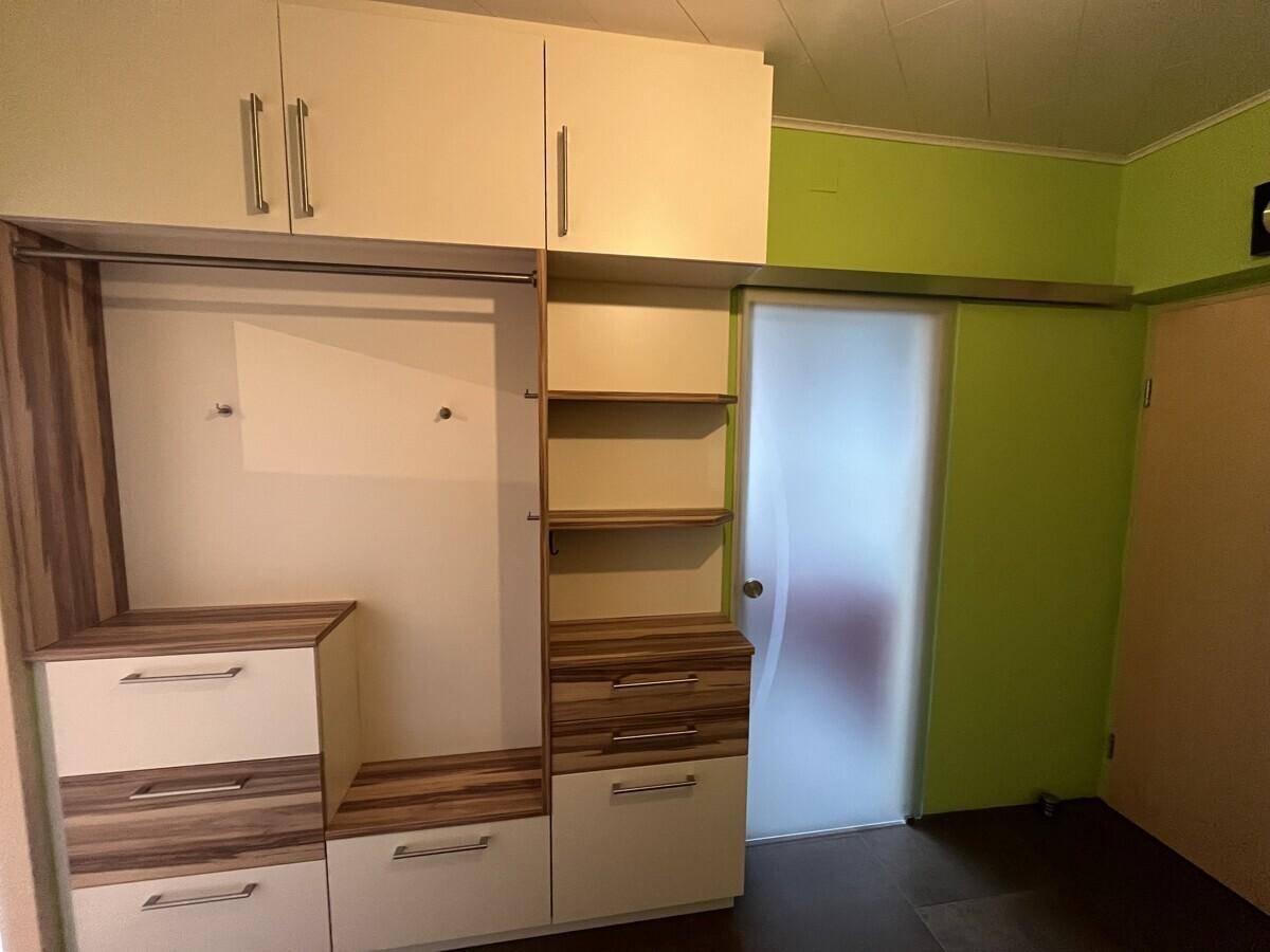 Eingangsbereich mit praktischen Einbauschränken und einer Schiebetür in hellem Holzdesign.