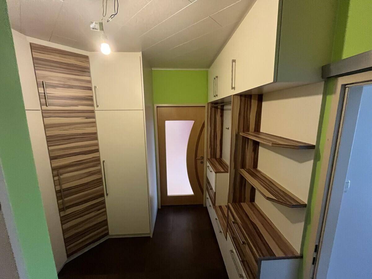 Langer Flur mit integrierten Schränken und Regalen in Holzoptik, ideal für zusätzlichen Stauraum.