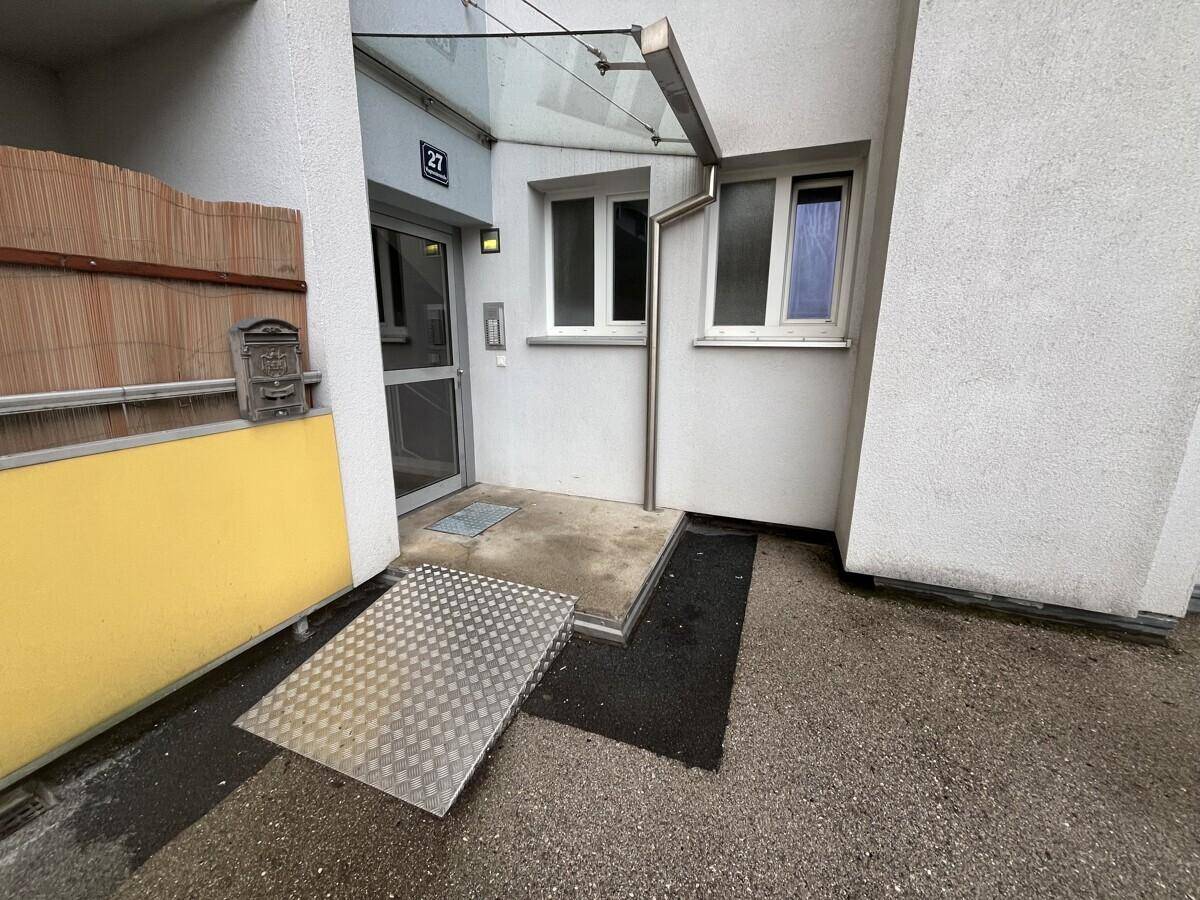 Barrierefreier Eingangsbereich mit einer Metallrampe und Glasvordach für einfachen Zugang.