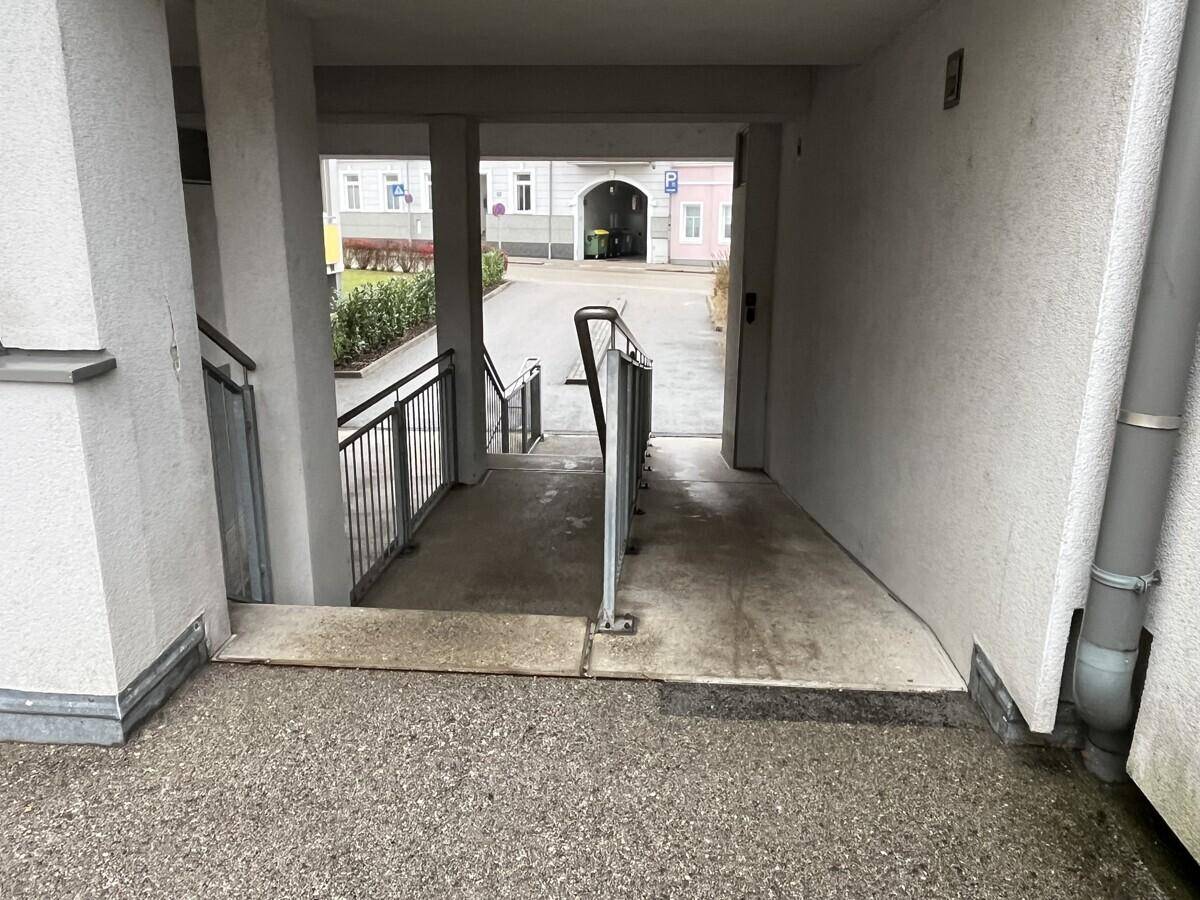 Überdachter Durchgangsbereich mit Treppe und Rampe, der zum Innenhof führt.