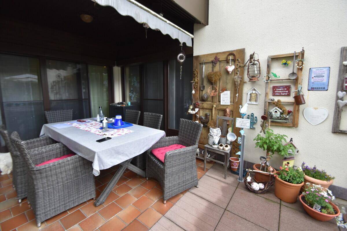 Gemütliche, überdachte Terrasse mit Esstisch und Stühlen, ideal für Mahlzeiten im Freien.