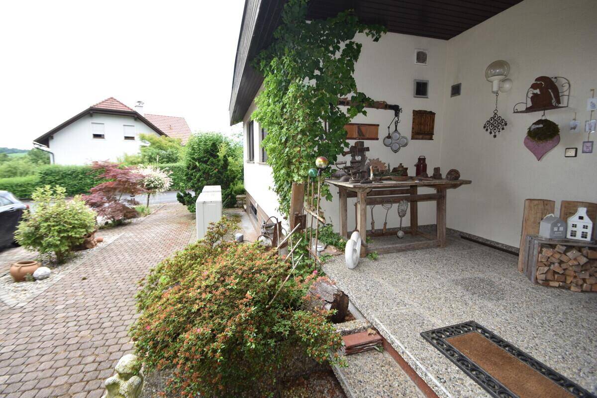 Dekorativer Eingangsbereich des Hauses mit gepflastertem Weg und grüner Bepflanzung.