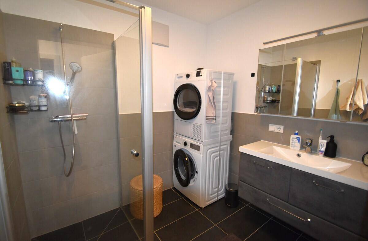 Modernes Badezimmer mit Dusche, Waschmaschine und Trockner.