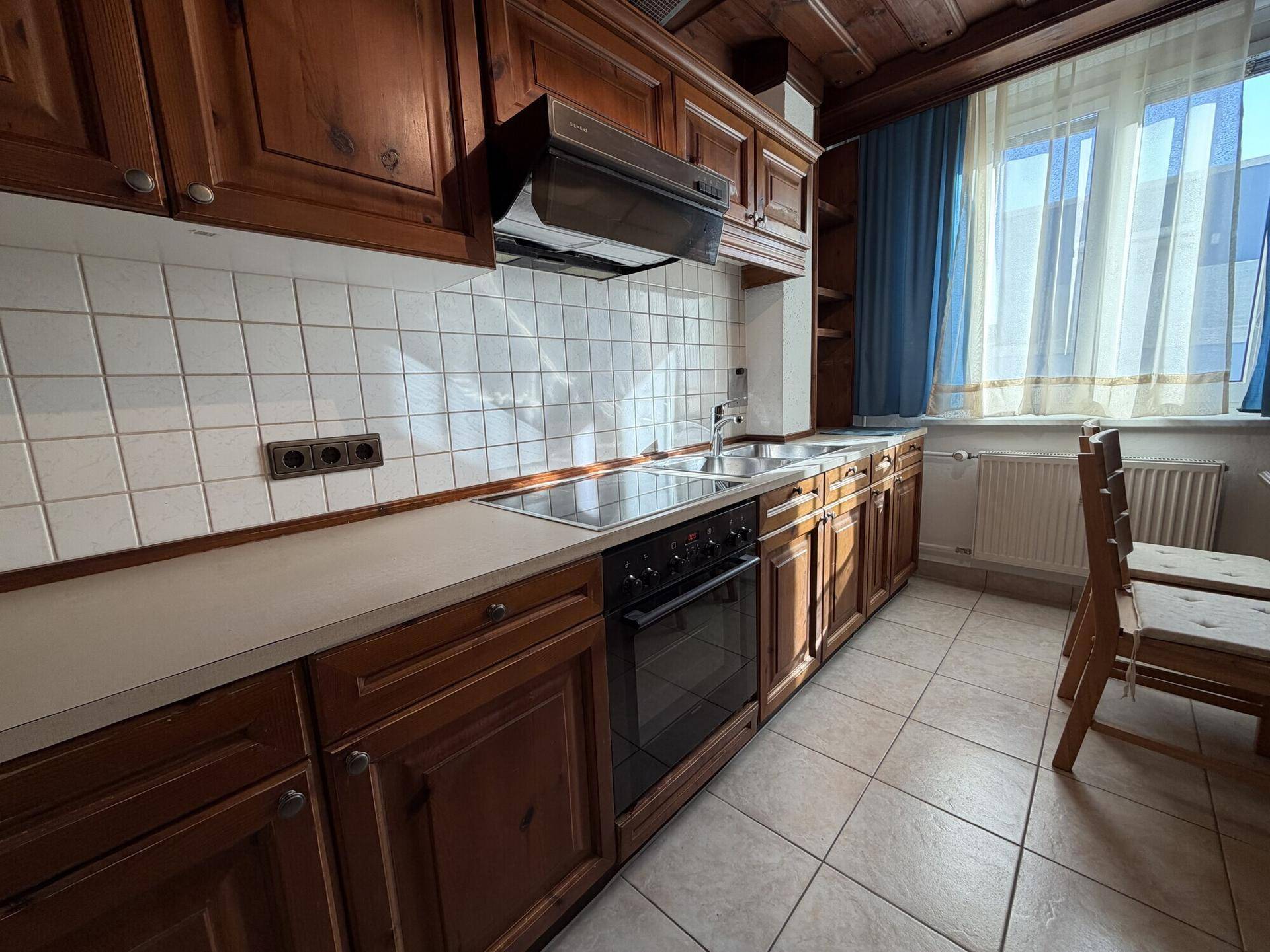 Detailansicht der traditionellen Holzküche mit Kochfeld, Spüle und Fliesenrückwand.