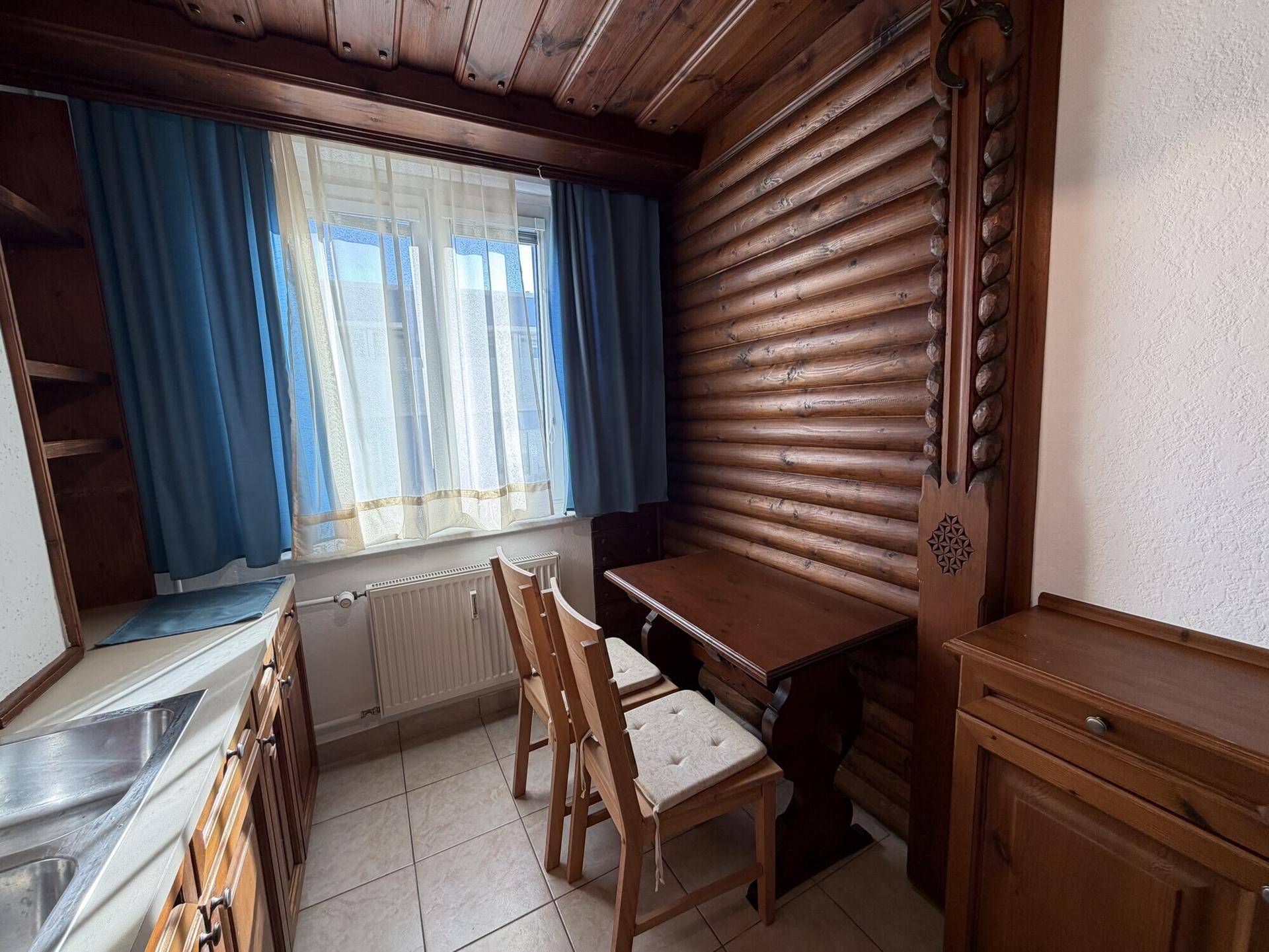 Gemütlicher Essbereich in der Küche mit Holztisch und Stühlen unter einem Fenster.