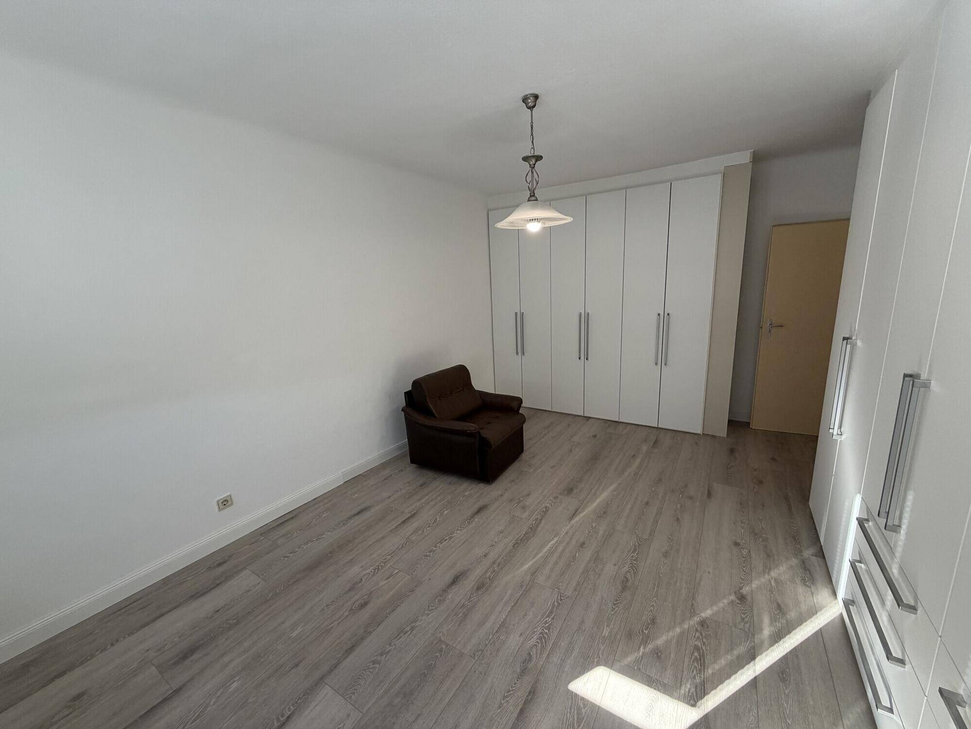 Geräumiges Zimmer mit Laminatboden und umfangreichen weißen Schränken für Stauraum.