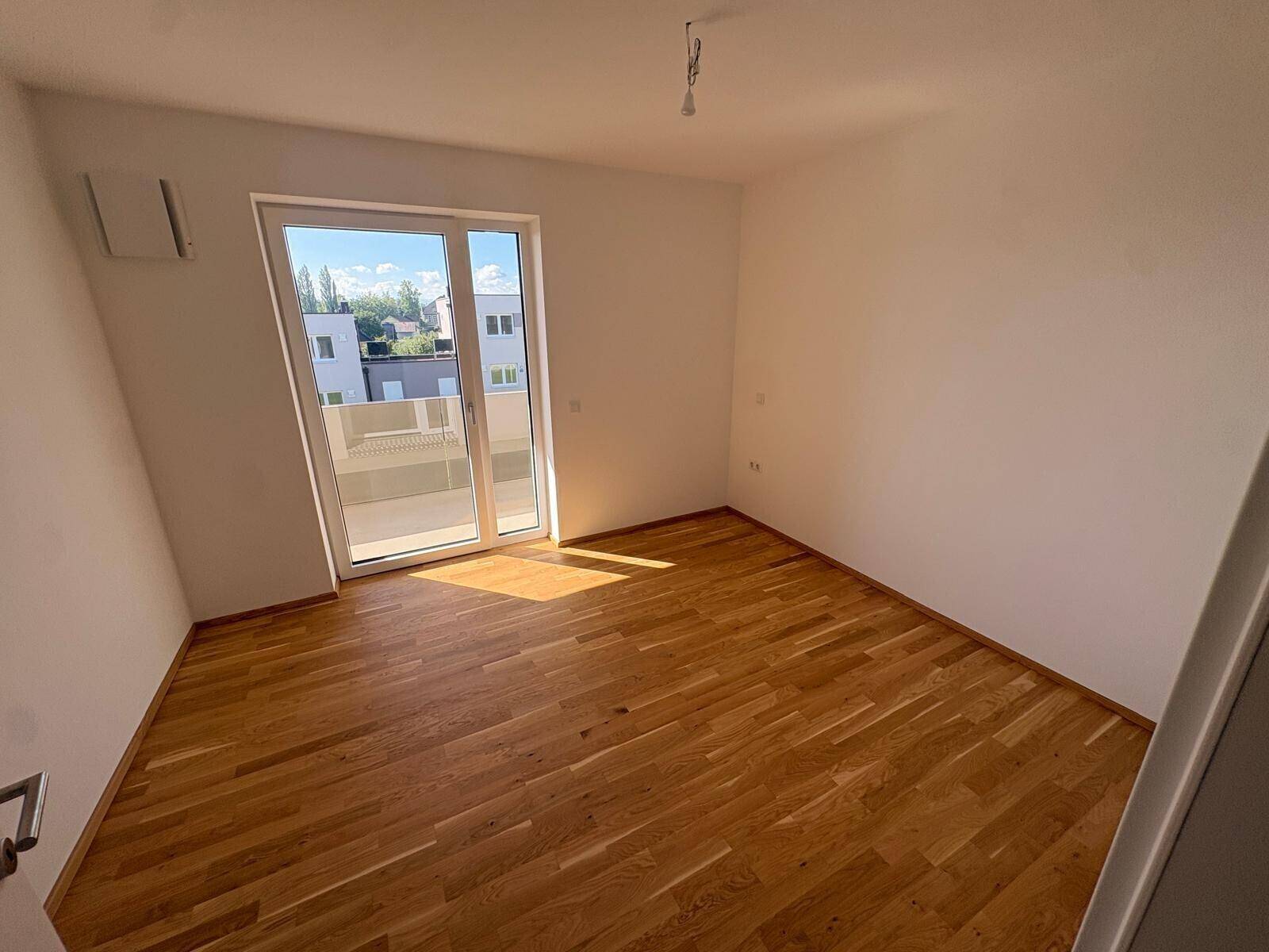 Helles Schlafzimmer mit Parkettboden und direktem Zugang zu einem Außenbereich.