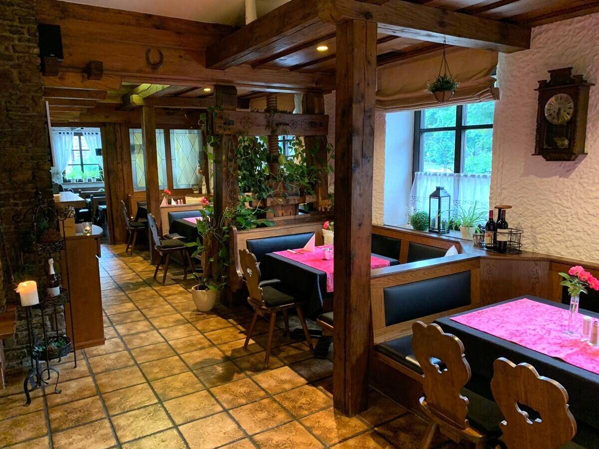 Gemütlicher Restaurantbereich mit Holzbalken, Nischen und traditionellen Holzmöbeln.