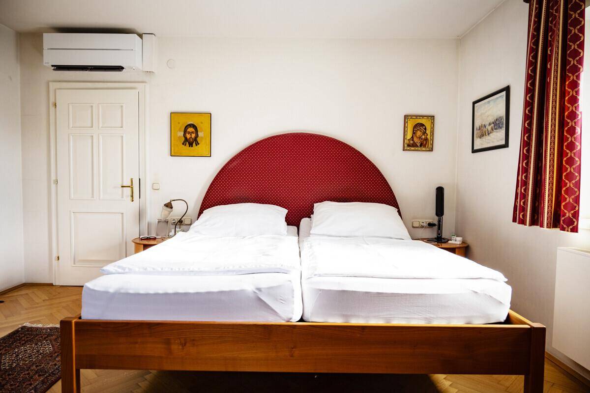 Schlafzimmer mit Doppelbett, Klimaanlage und traditionellen Dekorationselementen an der Wand.