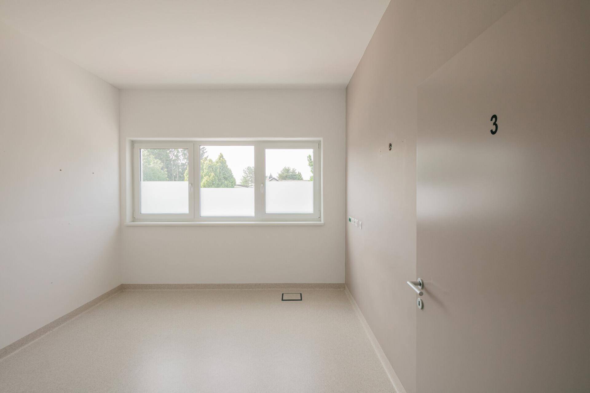 Heller Büroraum mit Vinylboden und Fenster, die Tür ist deutlich mit der Nummer drei gekennzeichnet.