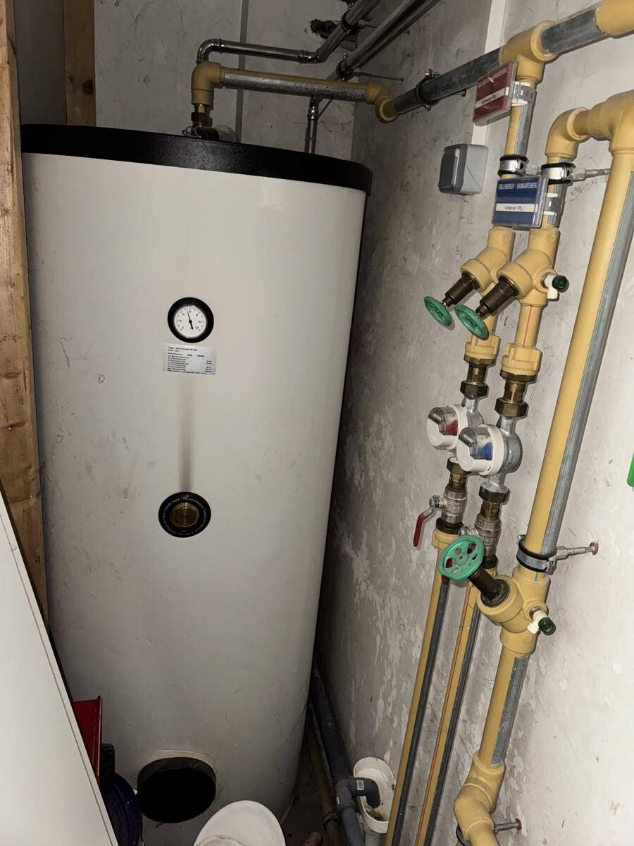 Warmwasserspeicher und Rohrleitungen für die Wasserversorgung im Technikraum.