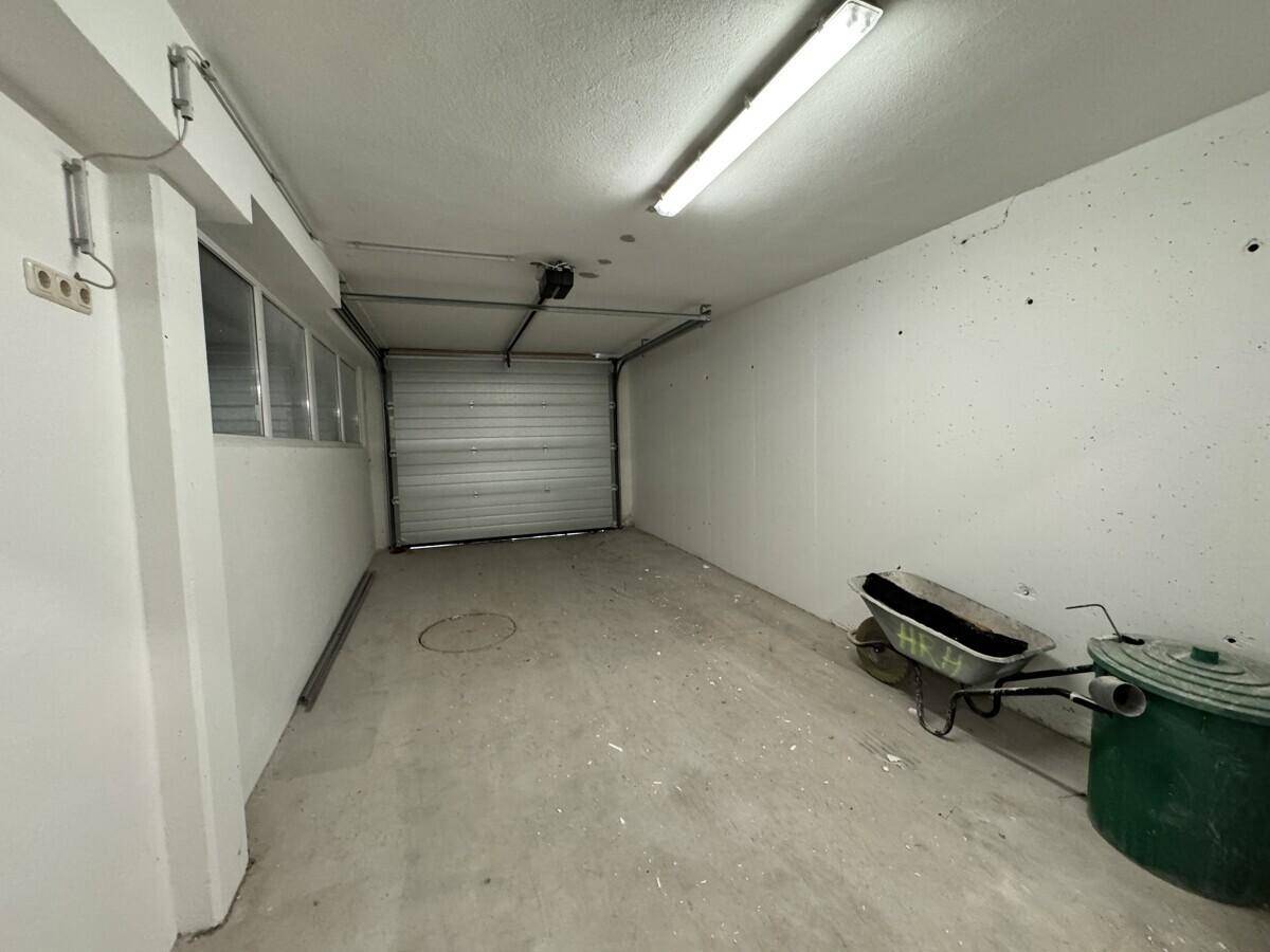 Einfache Garage mit Betonboden, Rolltor und ausreichend Platz für ein Fahrzeug.