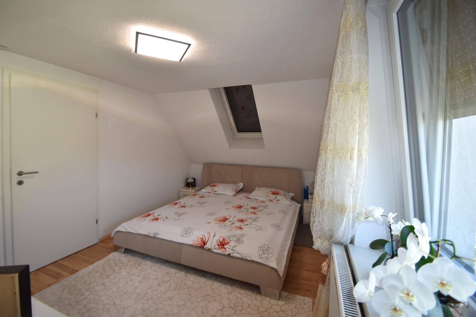 Schlafzimmer im Dachgeschoss mit Doppelbett, Dachfenster und Holzboden.