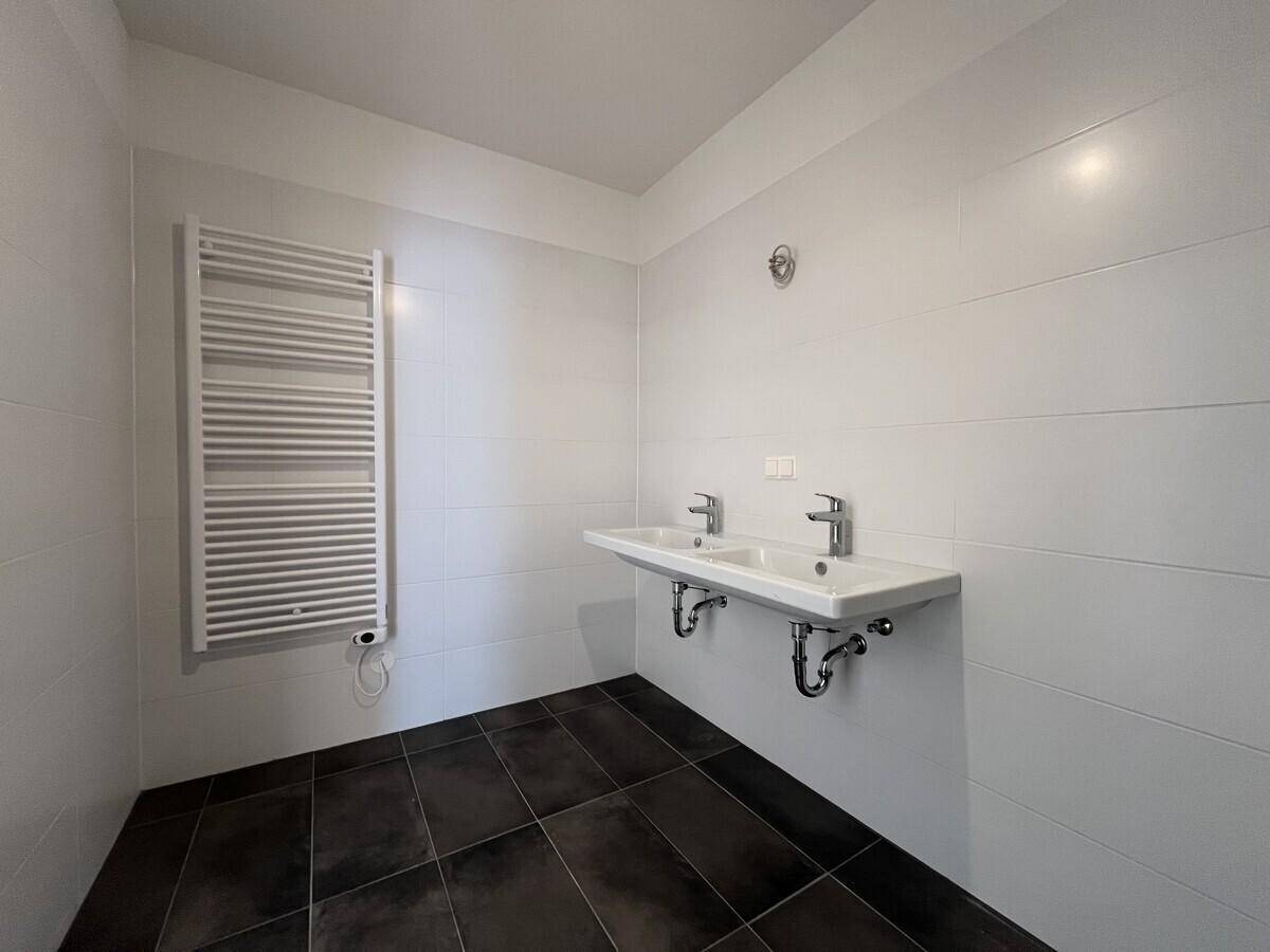 Modernes Badezimmer mit Doppelwaschbecken, Fliesenboden und beheiztem Handtuchhalter.