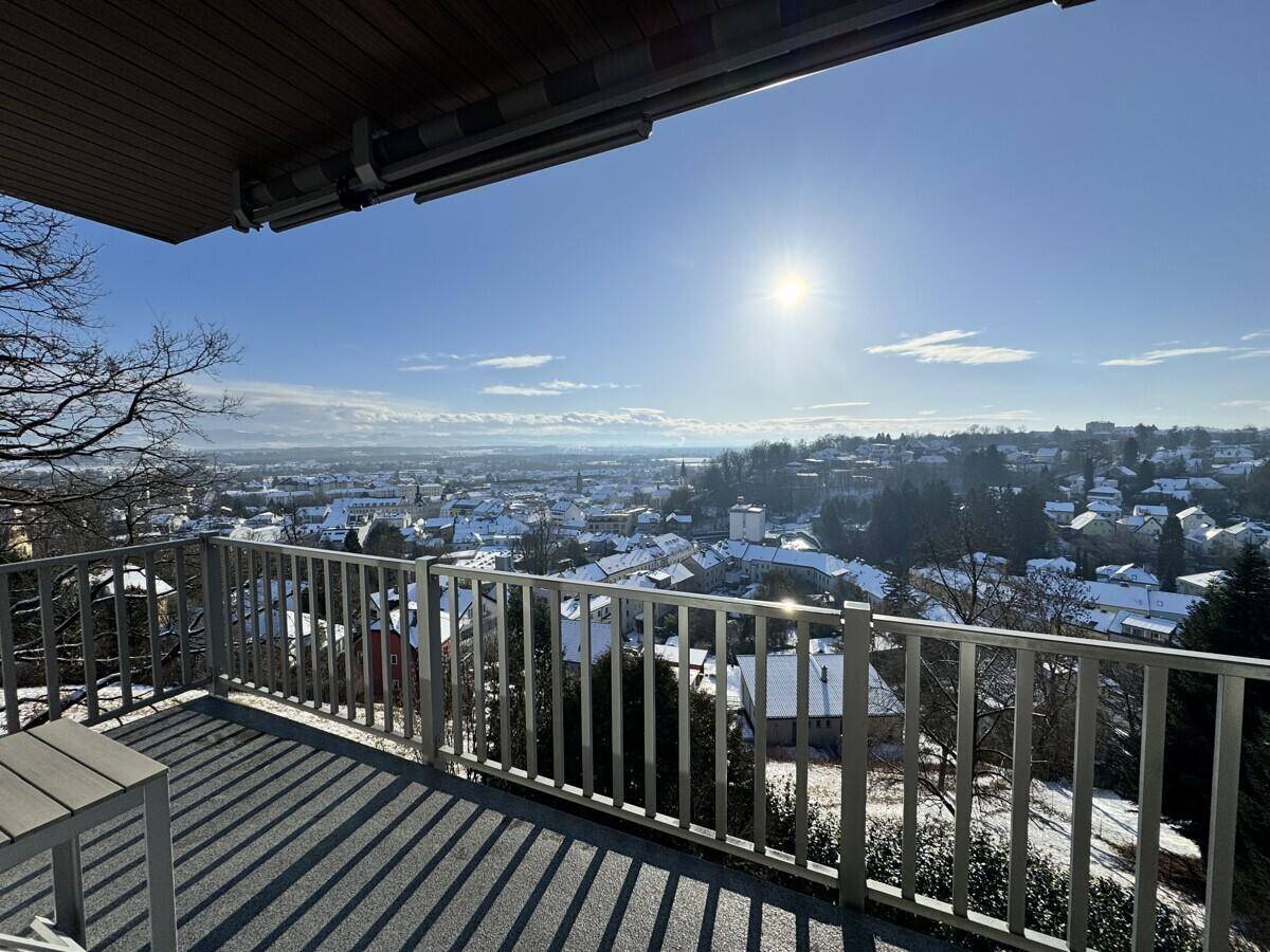 Geräumiger Balkon mit Panoramablick über eine schneebedeckte Stadtlandschaft unter strahlendem Sonnenschein.