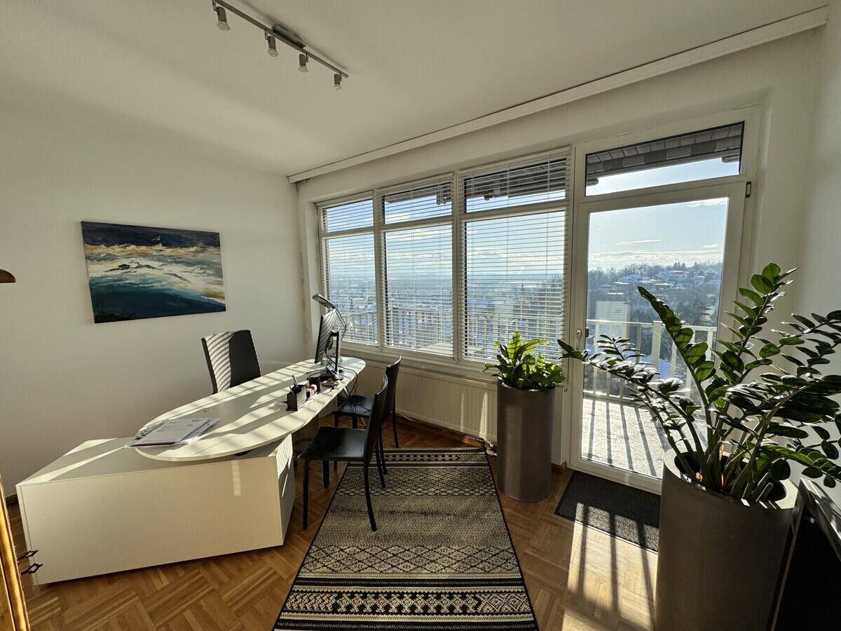 Helles Büro mit großflächigen Fenstern, die einen weiten Blick über die Stadt bieten, und modernen Möbeln.