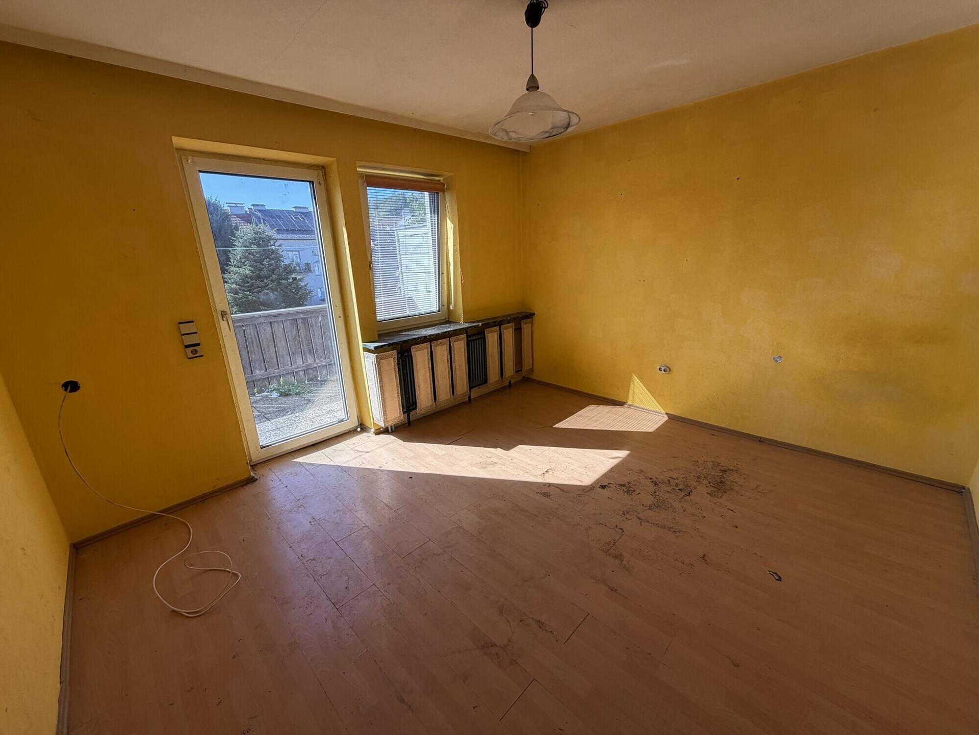 Helles Zimmer mit gelben Wänden und Balkonzugang, ideal für ein Kinderzimmer.