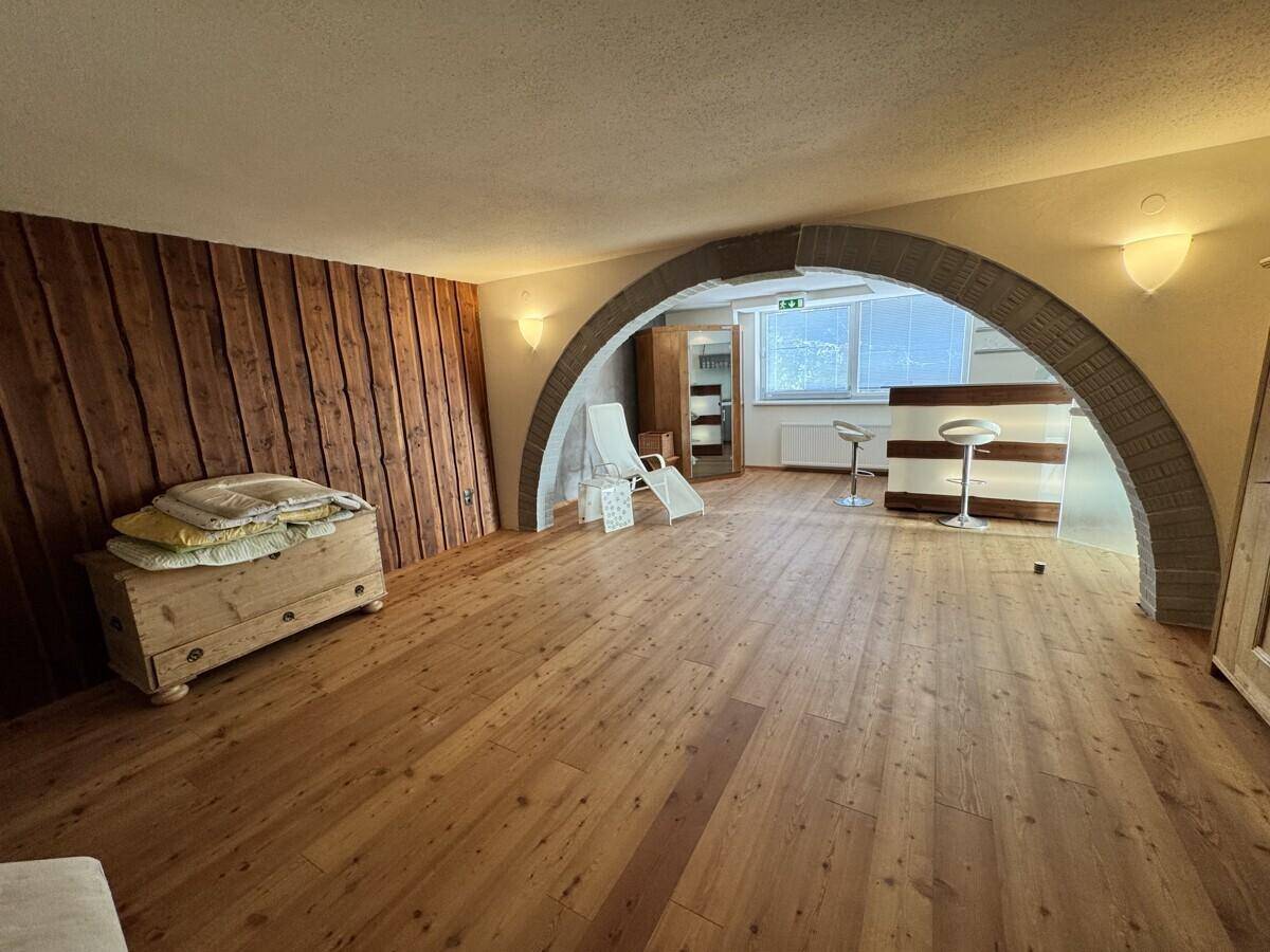 Großer Entspannungsraum mit Holzboden, Holzwandverkleidung und einem gemauerten Bogen.