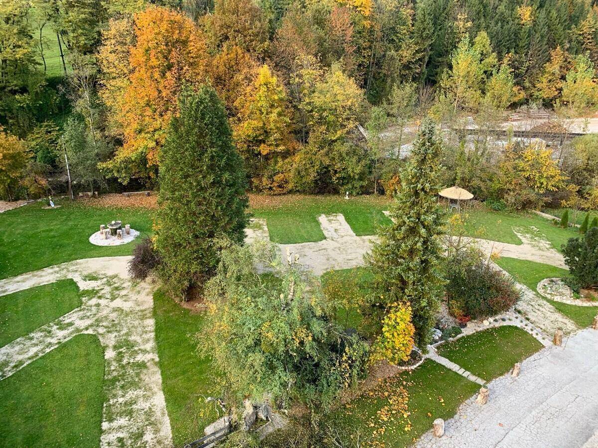 Weitläufiger Gartenbereich mit Rasenflächen, Bäumen und Sitzgelegenheiten im Herbstlaub.
