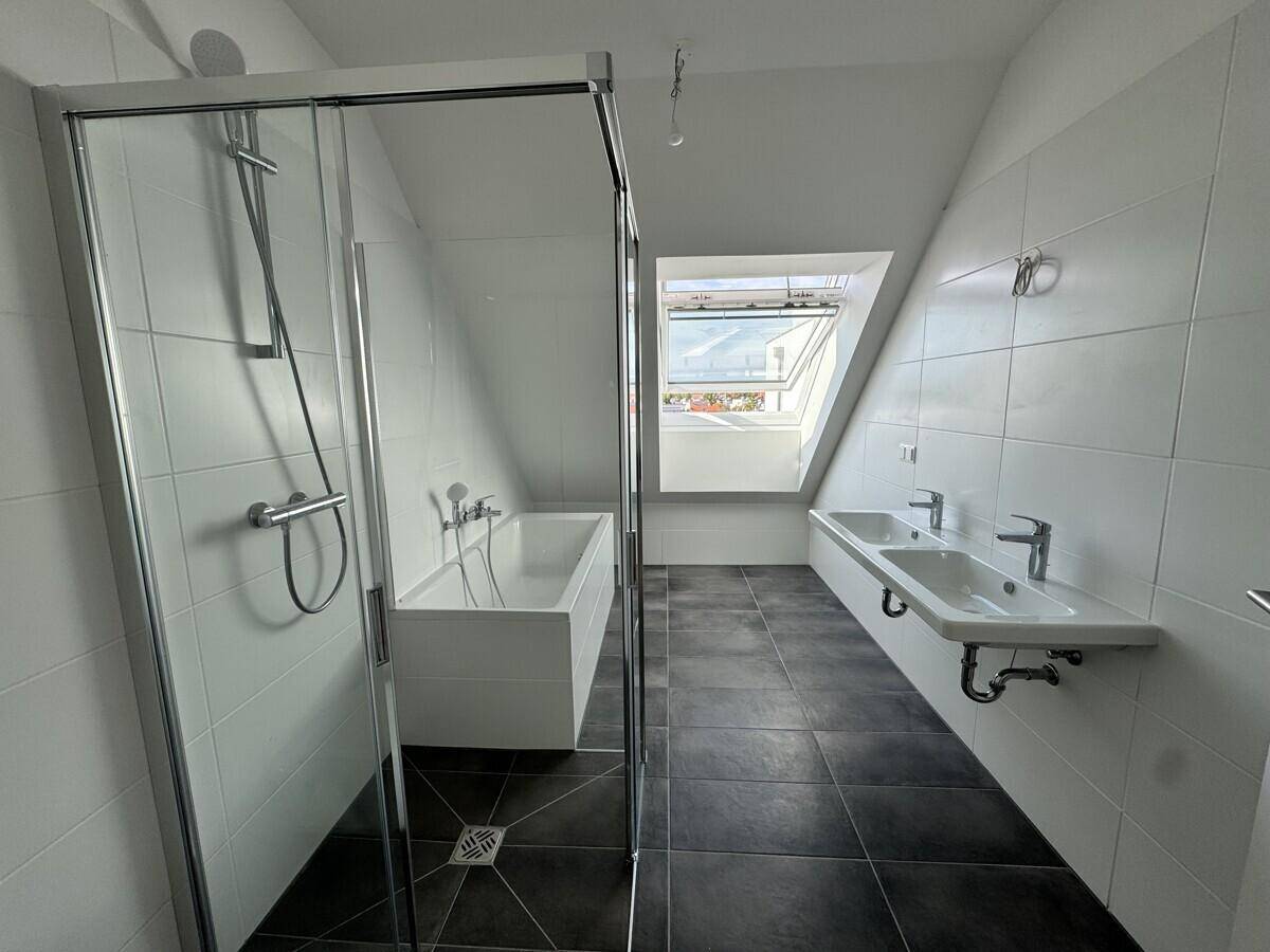 Modernes Badezimmer mit Badewanne, Dusche, Doppelwaschbecken und Dachfenster.