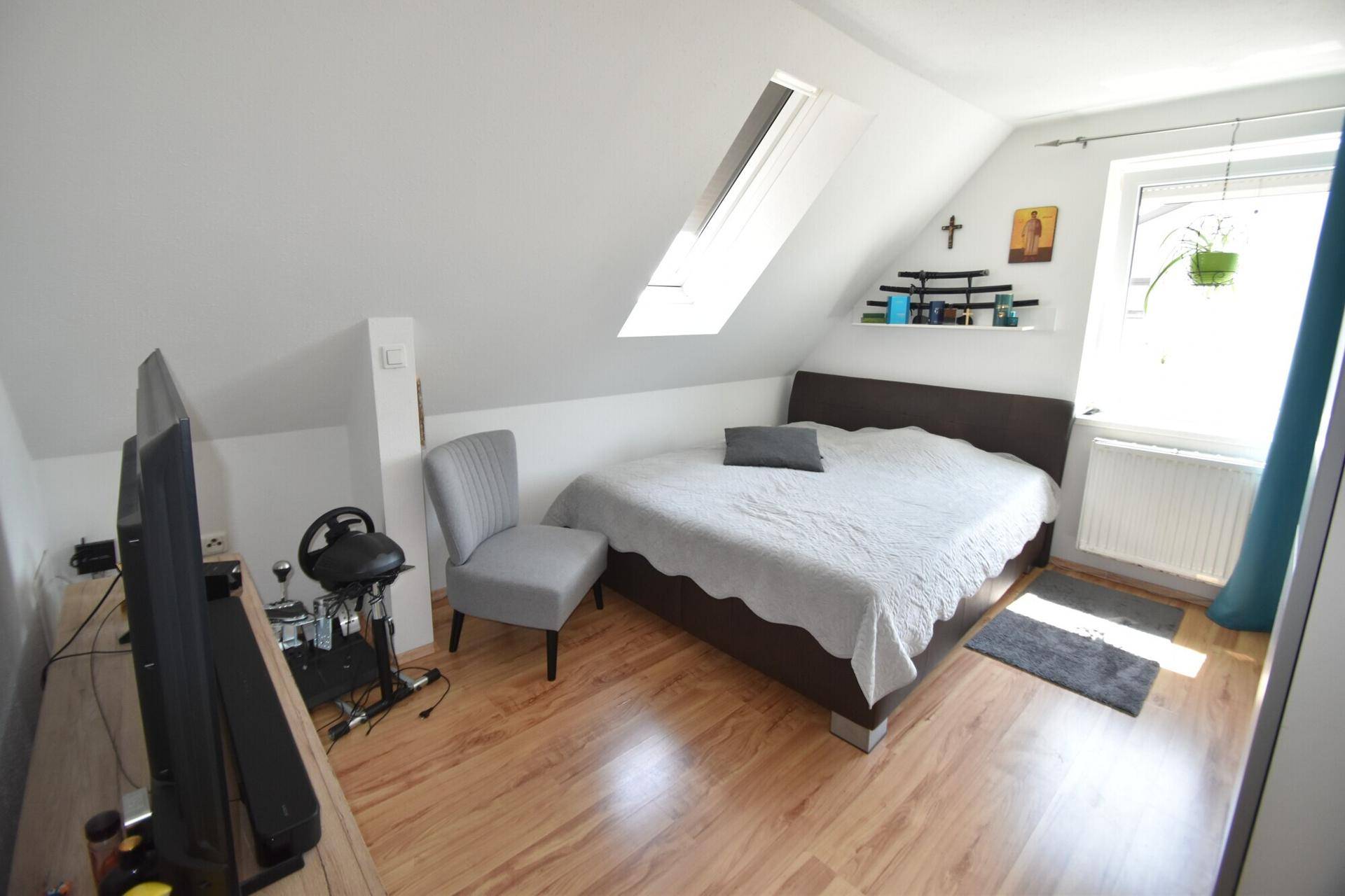 Schlafzimmer im Dachgeschoss mit Doppelbett, Dachfenster und Holzboden.