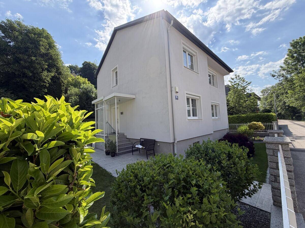 Helles Einfamilienhaus mit gepflegtem Vorgarten und sonnigem Eingangsbereich.