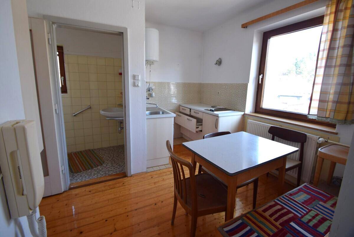Kleine Küche mit Essbereich, Fenster und Zugang zu einem Badezimmer.