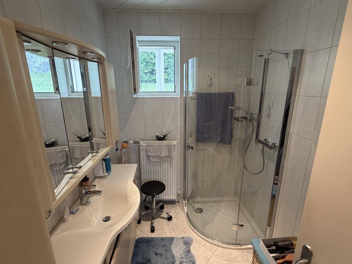 Modernes Badezimmer mit Dusche, Waschbecken und Fenster für Tageslicht.