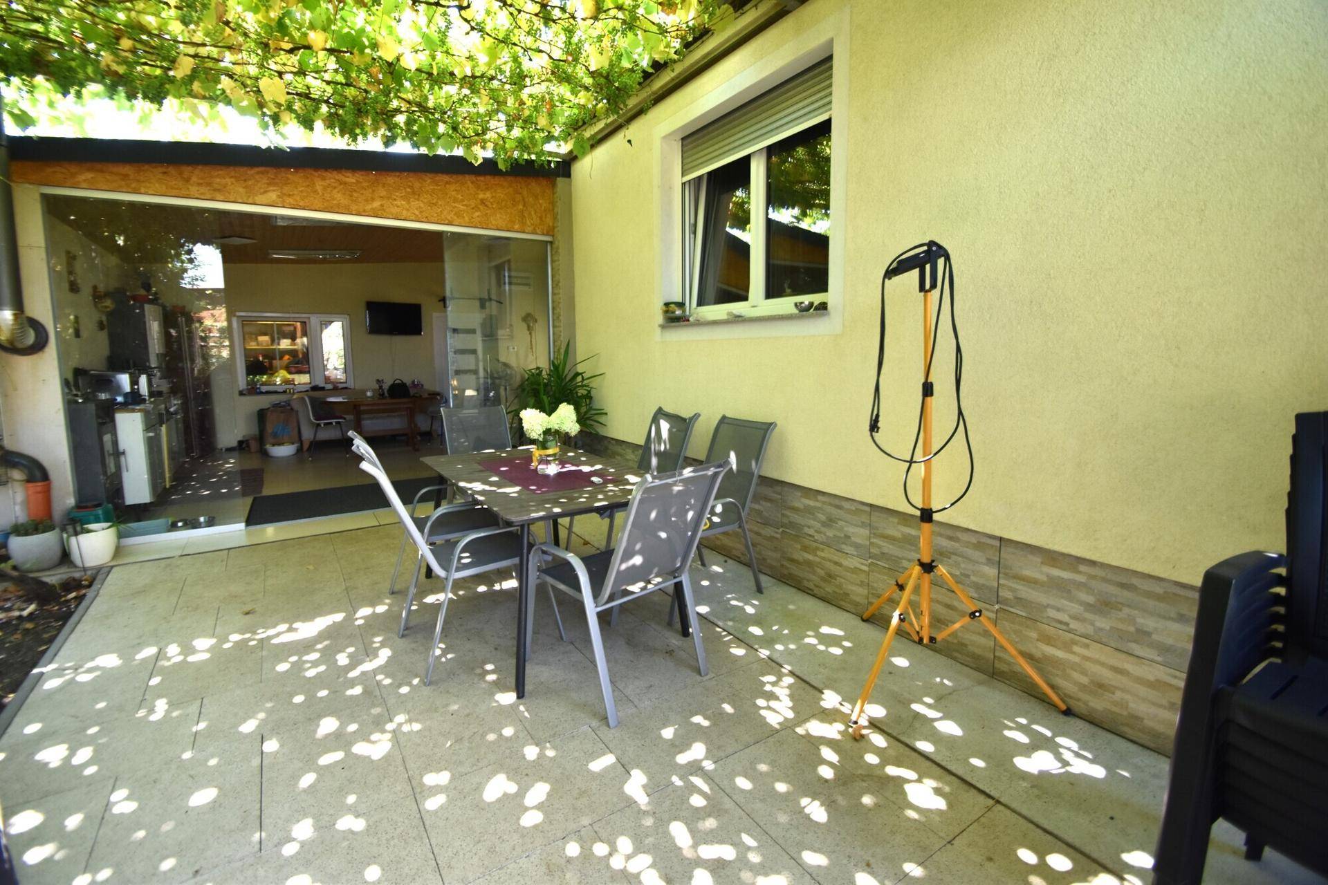 Überdachte Terrasse mit Essbereich im Freien und Zugang zur Küche.