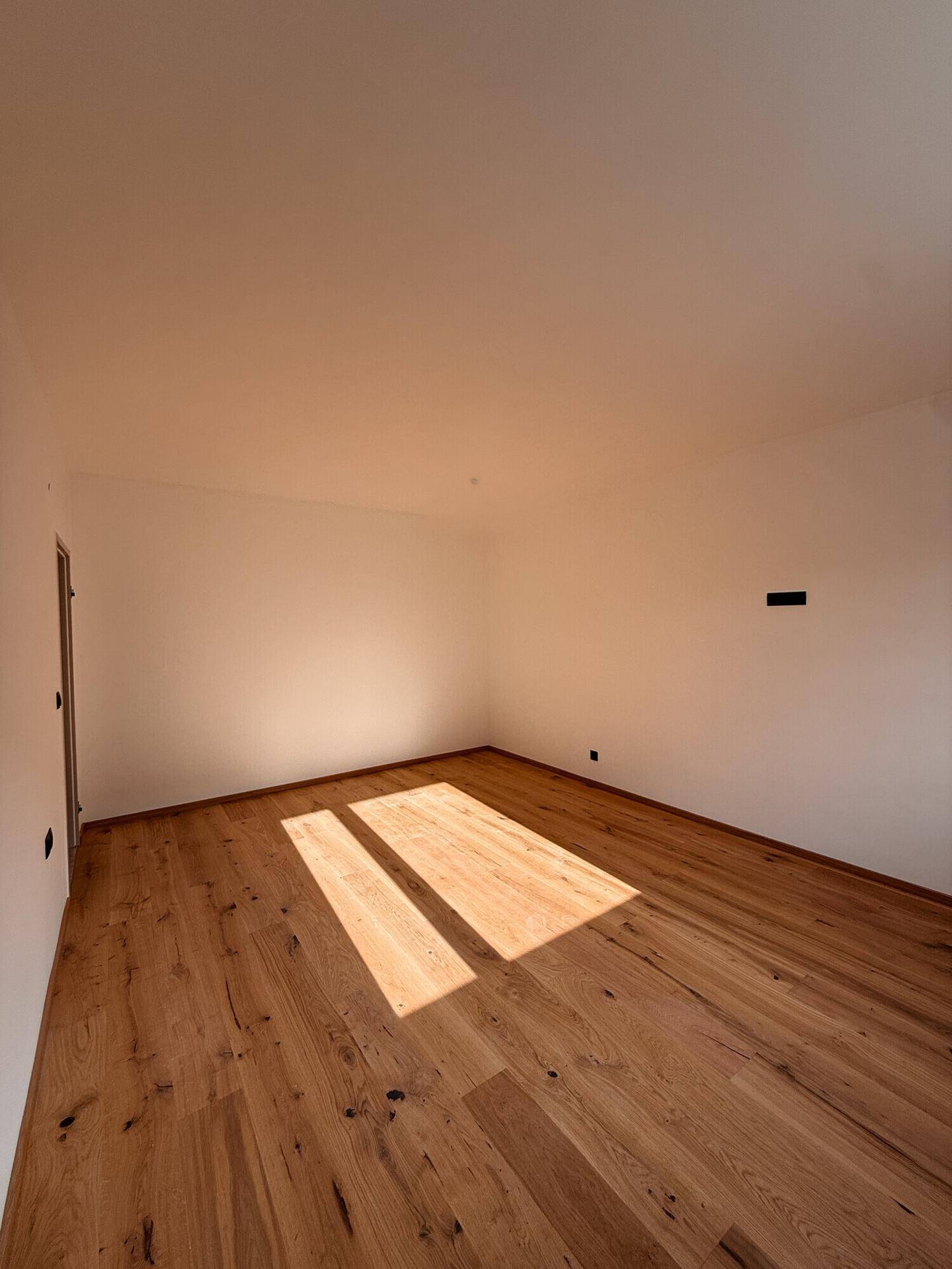 Geräumiges Zimmer mit hellem Holzboden und viel natürlichem Sonnenlicht.