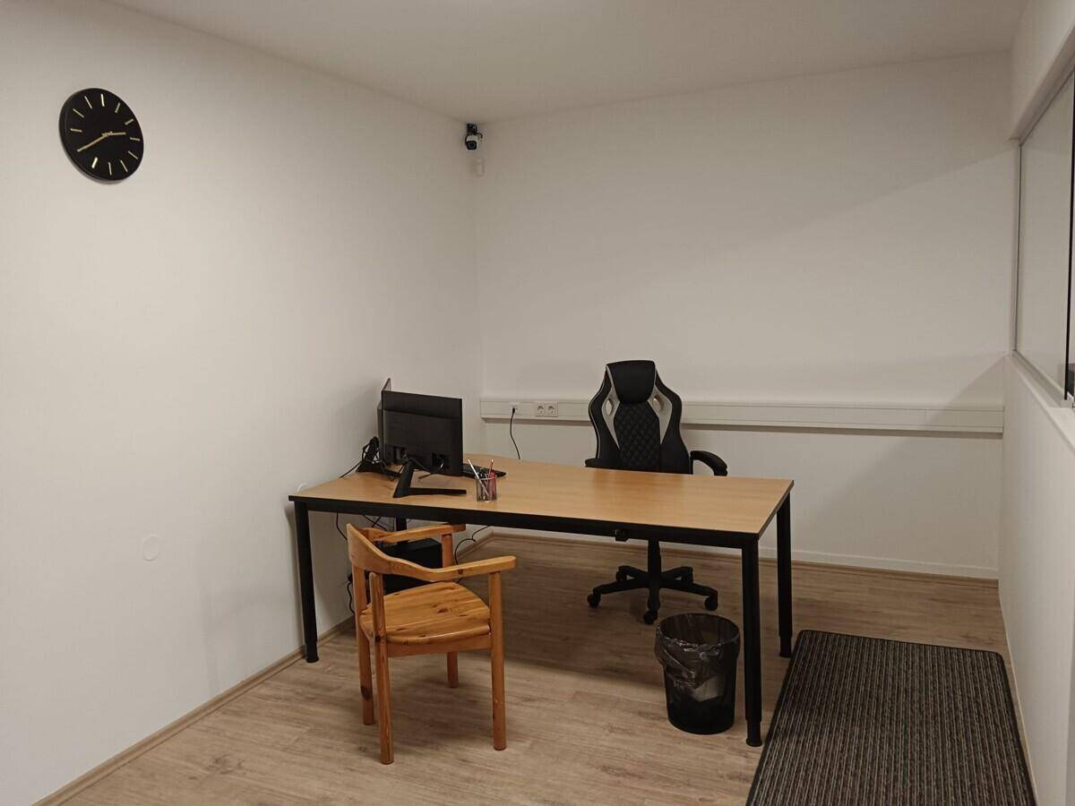 Heller Büroraum mit Schreibtisch, Bürostuhl und Laminatboden.