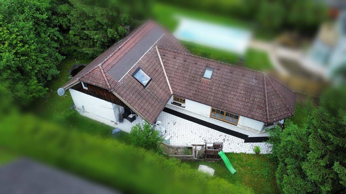 Luftaufnahme eines Hauses mit Ziegeldach, Dachfenstern und angrenzendem Gartenbereich.
