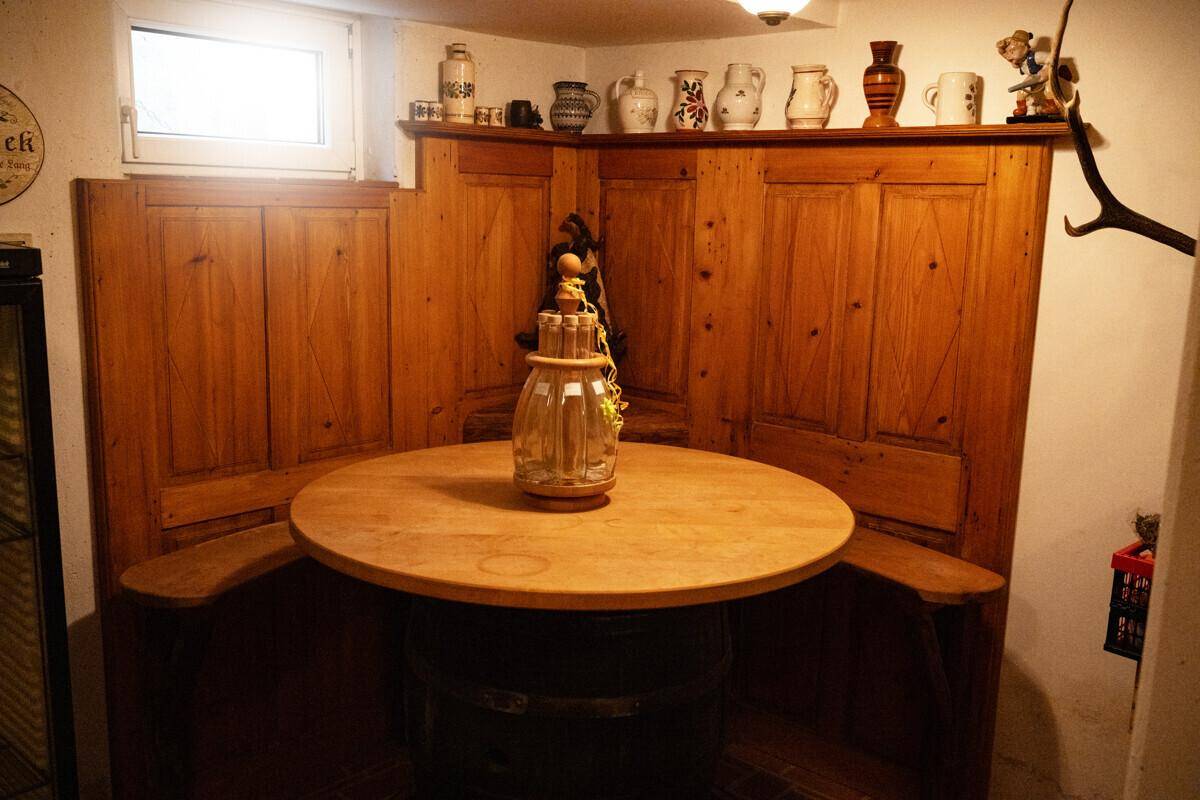 Rustikaler Essbereich im Keller mit Holzbänken, einem runden Tisch und kleinem Fenster.