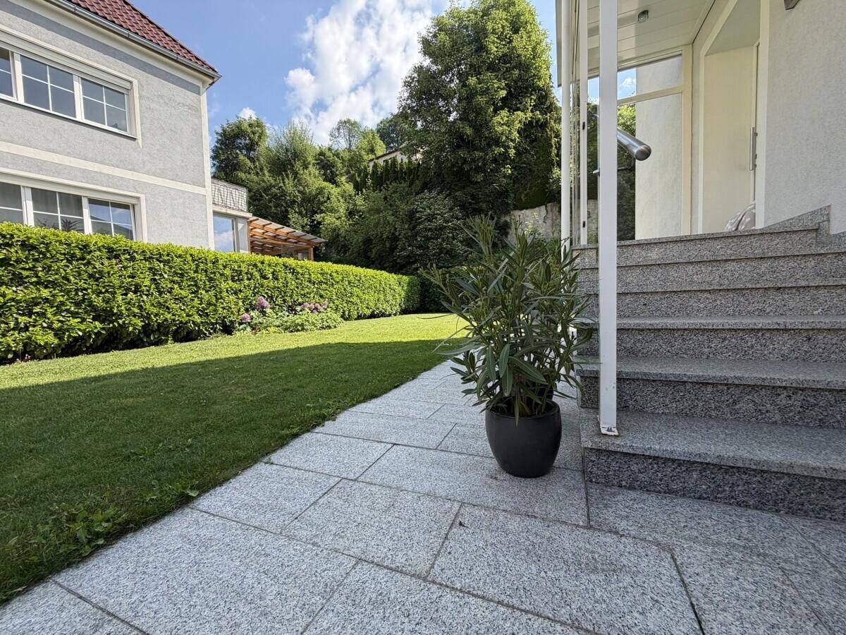 Gepflegter Vorgarten mit Granitstufen und einem bepflanzten Bereich neben dem Eingang.