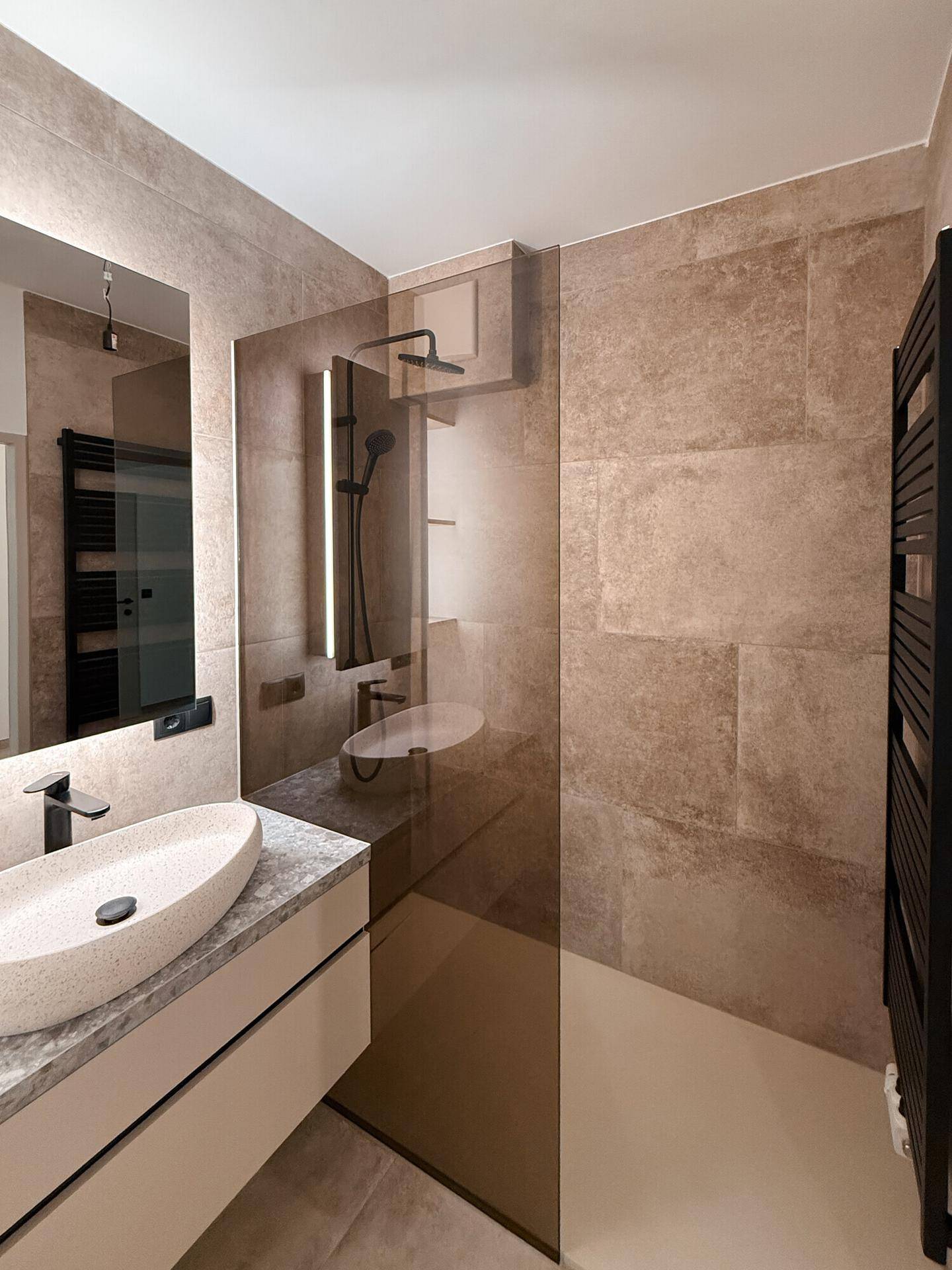 Modernes Badezimmer mit begehbarer Dusche, beigefarbenen Fliesen und beheiztem Handtuchhalter.
