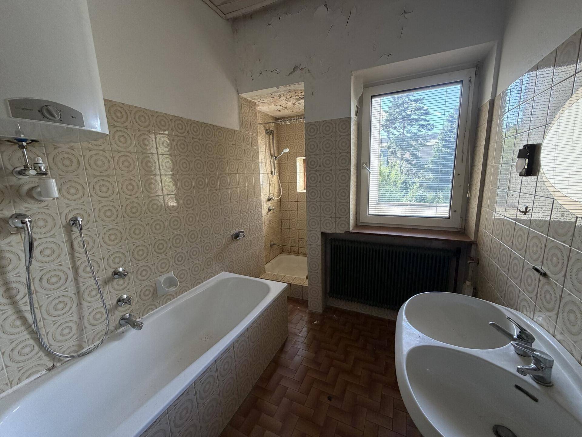 Badezimmer mit Badewanne, Dusche und Bidet, ausgestattet mit gemusterten Fliesen.