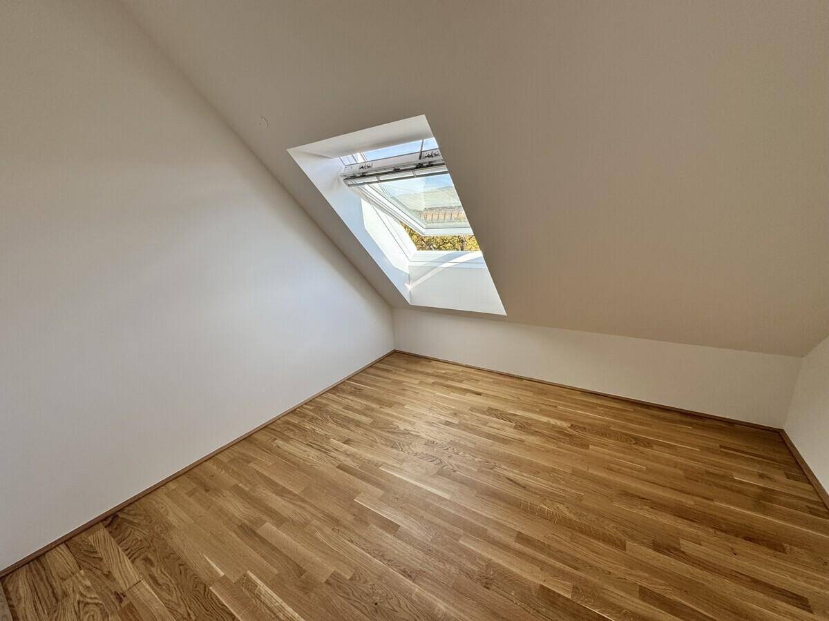 Gemütliches Schlafzimmer im Dachgeschoss mit Holzboden und schrägem Dachfenster.