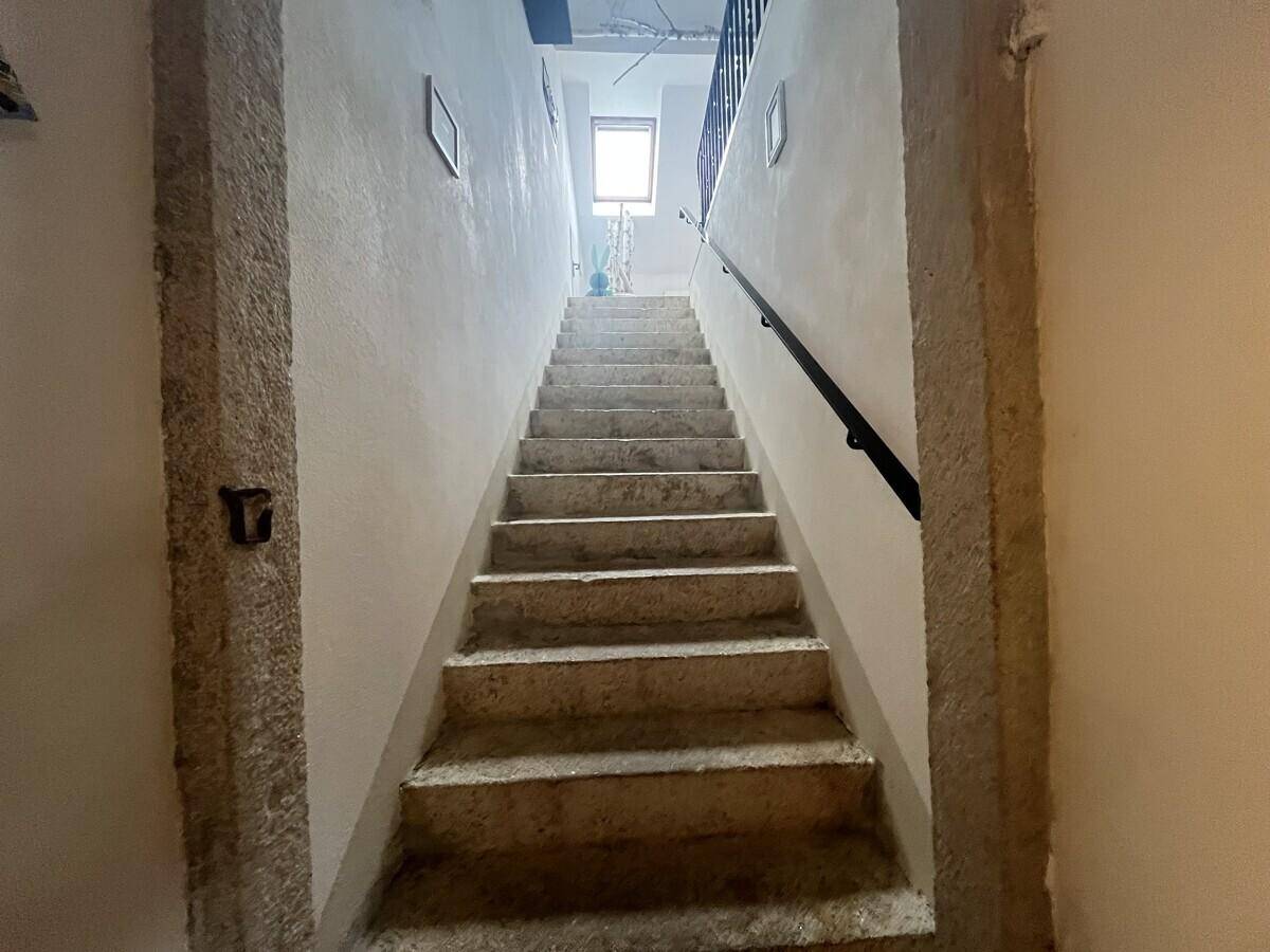 Rustikale Steintreppe führt nach oben, mit einem kleinen Fenster am Treppenabsatz.
