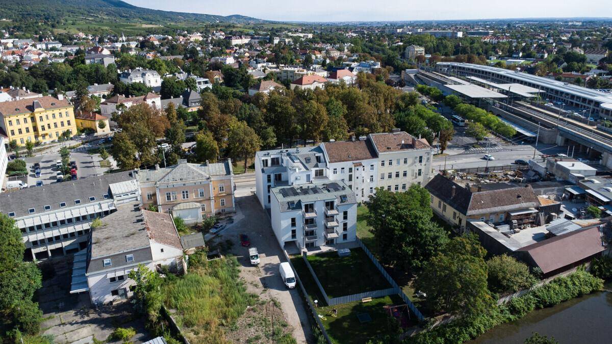 Weitläufige Luftaufnahme des Wohngebiets mit Neubauten, älteren Gebäuden und Bahnanlagen im Hintergrund.