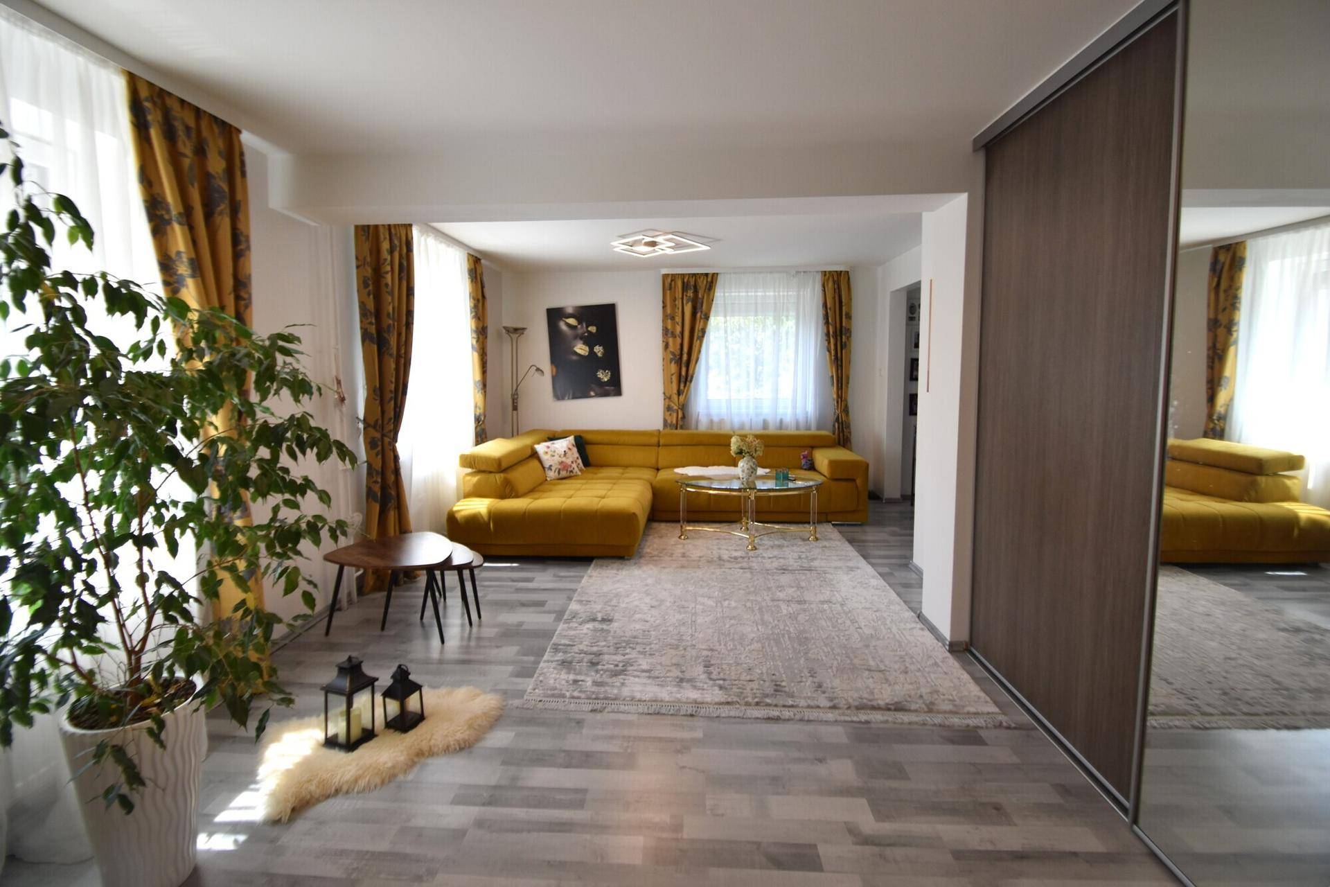 Helles Wohnzimmer mit modernem Sofa, Teppich und großem Fenster.