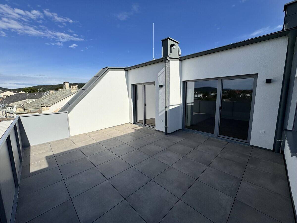 Geräumige Dachterrasse mit modernen Fliesen und Zugang zu den Innenräumen.